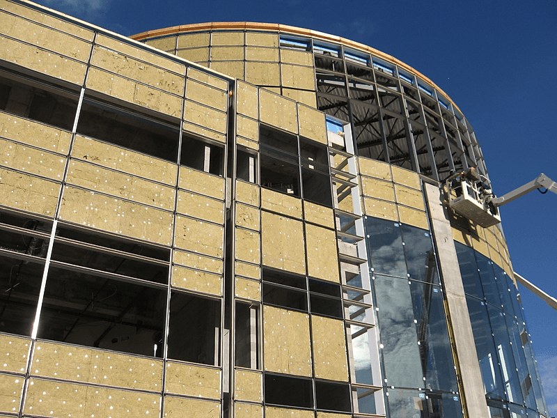 Stick-built curtain wall assembly where perimeter fire containment is used